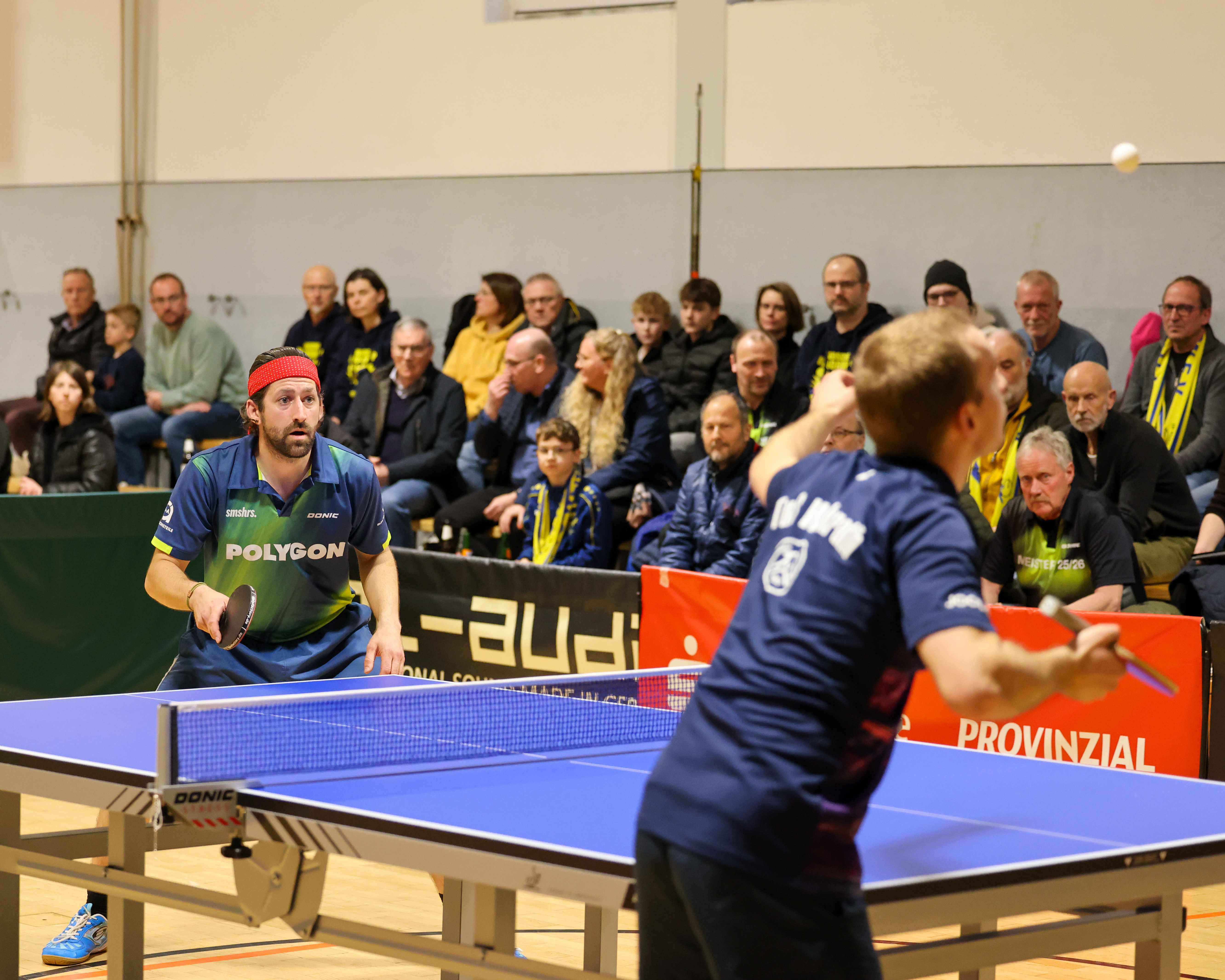Julian Buhl steht an der Tischtennis und holt zum Schlag gegen einen Tischtennisball aus.